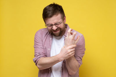 Portrait of mature man standing against yellow background