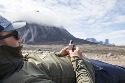 Man uses gps navigation device to plan his climbing route.