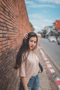 Portrait of beautiful young woman standing against wall