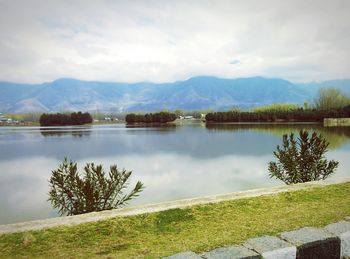 Scenic view of lake and mountains against cloudy sky