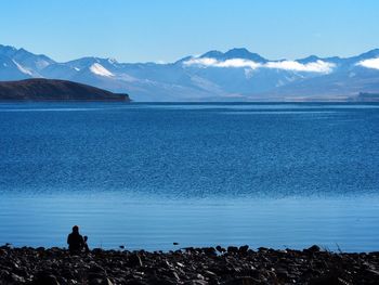 Scenic view of sea and mountains against blue sky