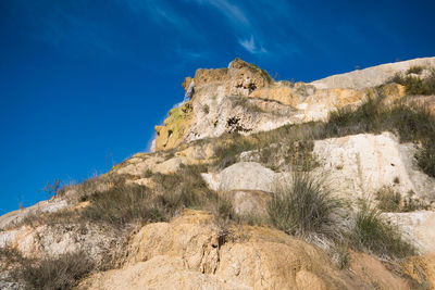 Low angle view of rock formations against blue sky