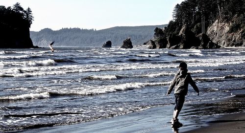 Man standing on cliff by sea