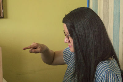 Portrait of young woman against wall at home