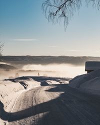 Snow covered road against blue sky during sunny day