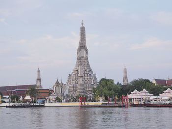 View of buildings by river against sky