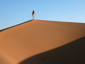 Low angle view of woman standing on sand dune