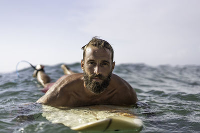 Portrait of shirtless man in sea against sky