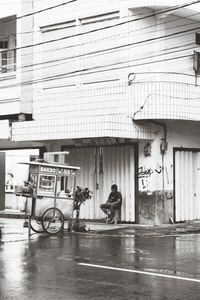 People on street by building in city