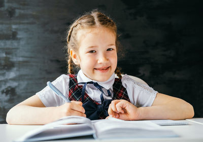 Portrait of a smiling girl sitting on table
