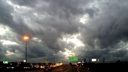 Traffic on road against dramatic sky