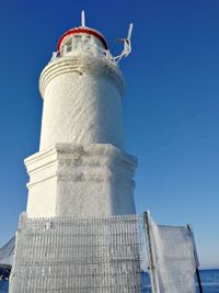 Low angle view of lighthouse against buildings