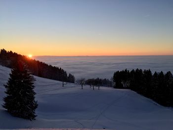 Scenic view of snow covered landscape against sky at sunset