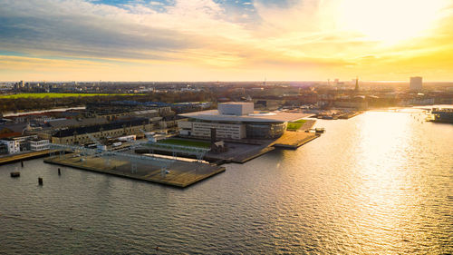 High angle view of river and buildings against sky during sunset