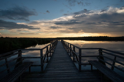 Pier over lake against sky during sunset