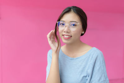 Portrait of smiling young woman against pink background