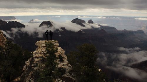 Panoramic view of people standing on mountain against sky