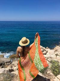 Rear view of woman standing on beach against clear sky