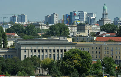 Trees and buildings against clear sky