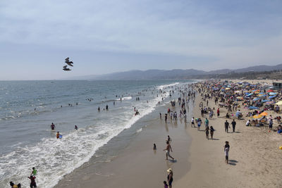 People enjoying on beach against sky