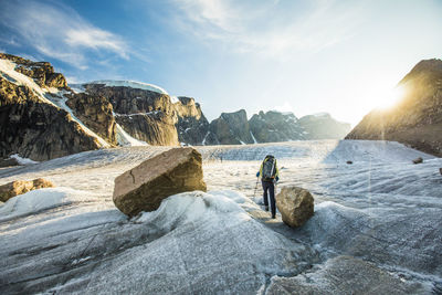 People on rock at beach against sky