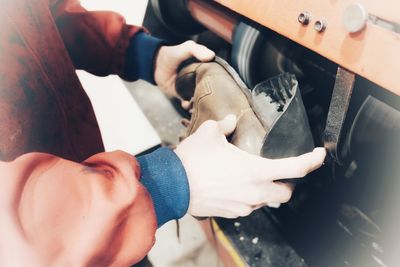 Midsection of manual worker making shoe at workshop