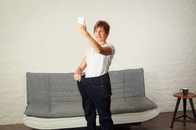Full length of young man standing against wall at home
