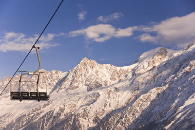 Overhead cable car in snowcapped mountains against sky