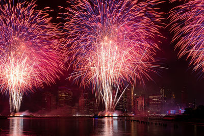 Firework display at night against cityscape