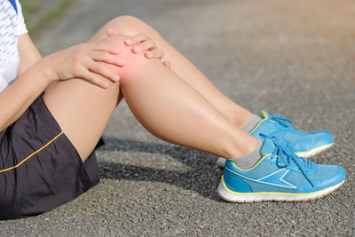 Low section of woman suffering from pain on road