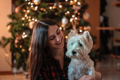 Portrait of woman with dog on christmas tree