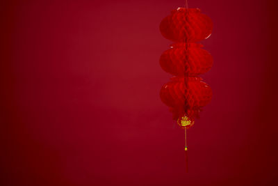 Low angle view of illuminated lanterns against red background