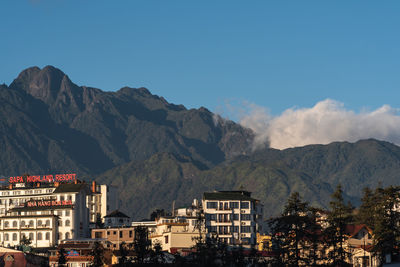 Buildings and mountains against blue sky