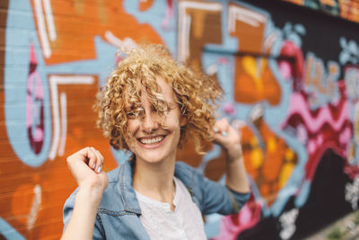 Happy woman standing against graffiti on wall