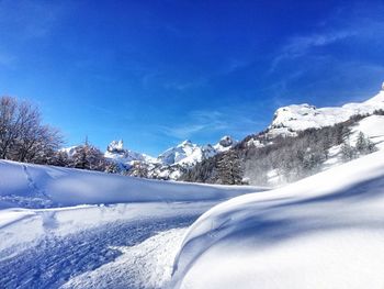 Snow covered landscape against blue sky