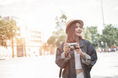 Young woman photographing on city street