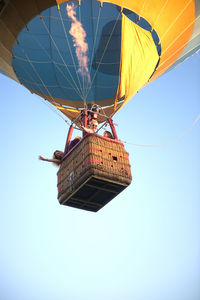Low angle view of friends flying in hot air balloon against clear sky