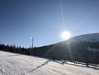 Snow covered landscape against sky on sunny day