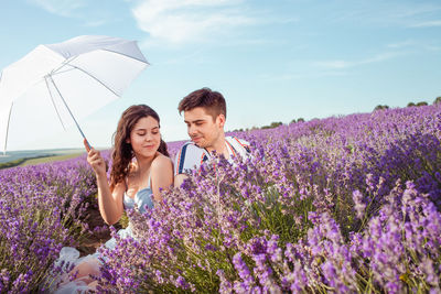A couple in love under a white umbrella on a lavender field love