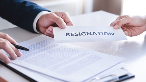 Cropped image of man holding text on paper at table