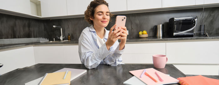 Portrait of young woman using mobile phone in office