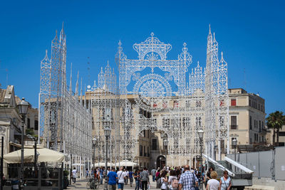 Group of people in front of buildings against clear blue sky