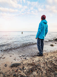 Woman watch fishing man wading in cold water of baltic sea. man in water pulling bait on fishing rod