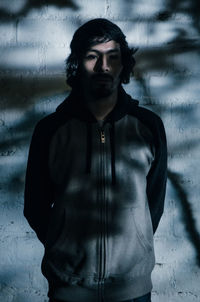 Portrait of young man standing against wall