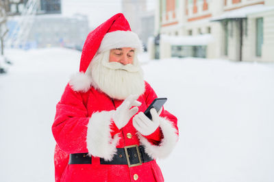 Portrait of woman wearing santa claus costume standing on snow