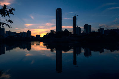 Reflection of buildings in lake against sky during sunset