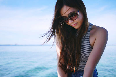 Woman wearing sunglasses against sea against sky