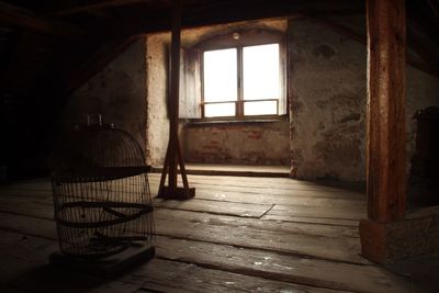 Damaged birdcage on wooden flooring in old building