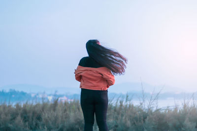 Rear view of woman standing on field against sky