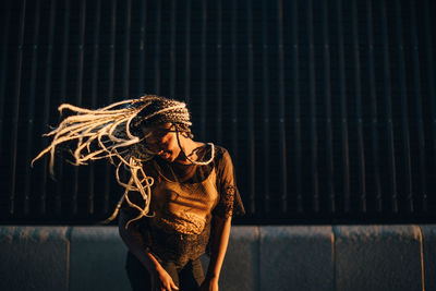 Smiling teenage girl dancing with tousled long hair at skateboard park